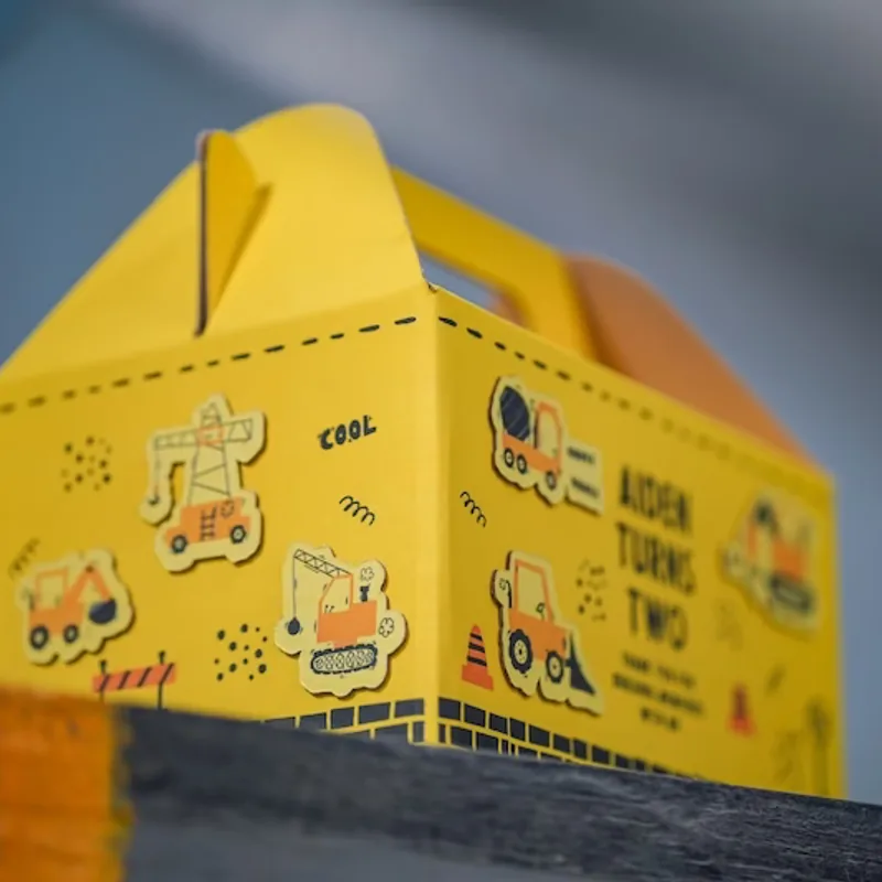 Gable box kuning cetak full-color bertema kendaraan konstruksi untuk hampers ulang tahun anak.