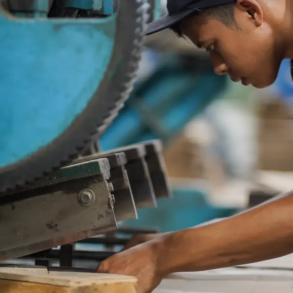 Operator JMP memasukkan lembar carton sheet ke mesin press di lantai produksi — sheet inilah bentuk kenaikan harga kertas saat sampai ke kami.