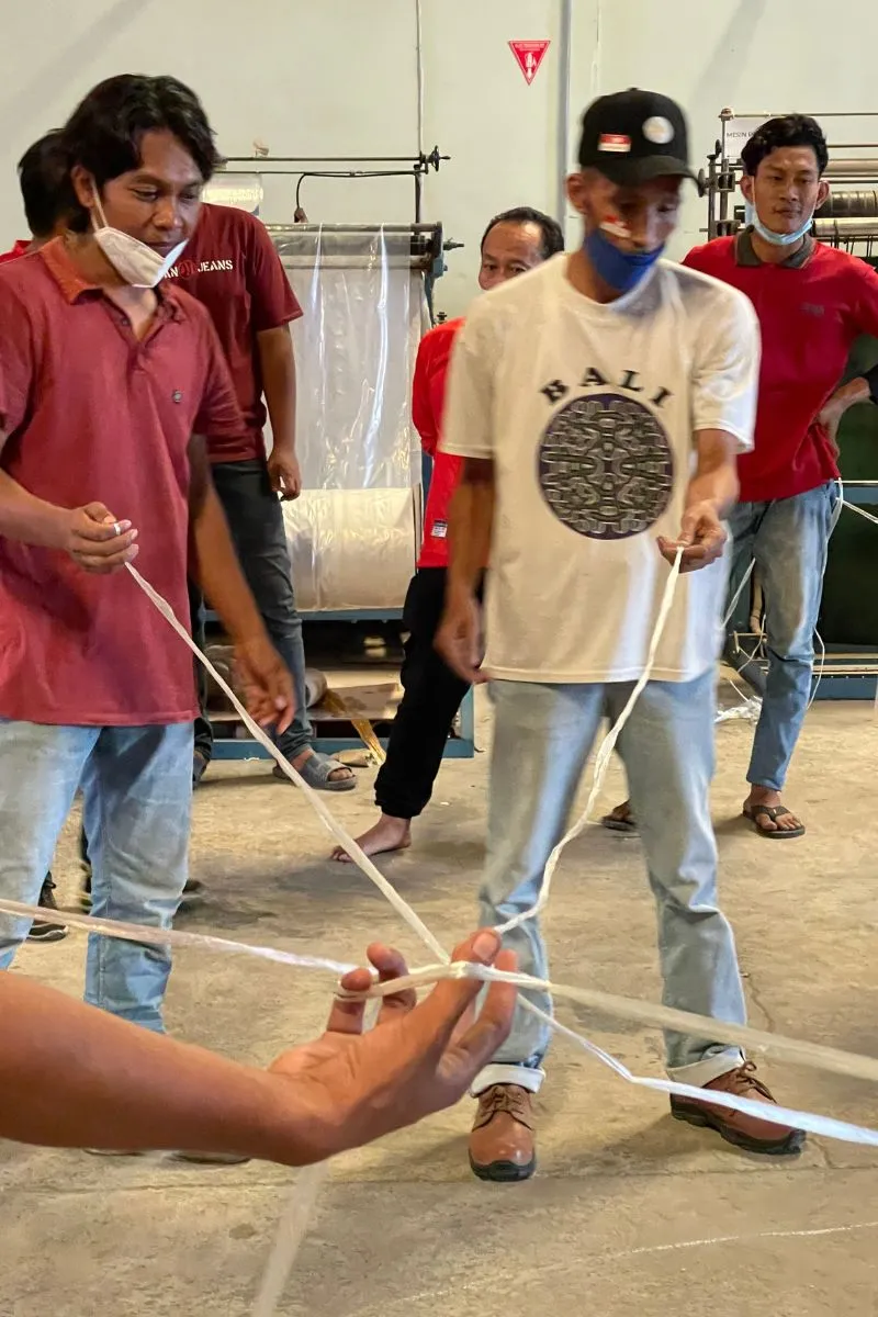 Close-up of players' hands gripping the ends of the ropes during the team game, with a roll of film in the background.