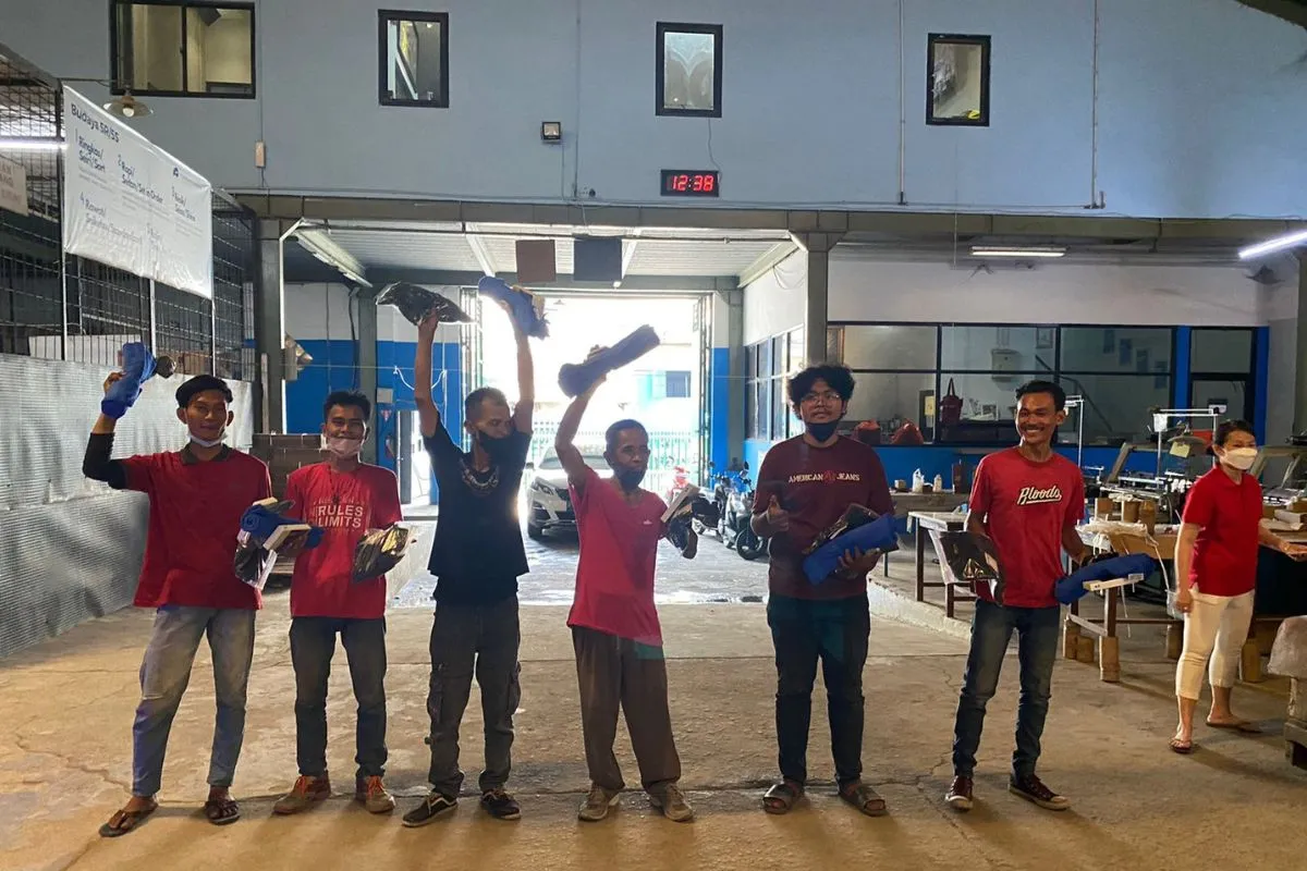 Winners lined up in the factory doorway, holding their wrapped prizes up high.