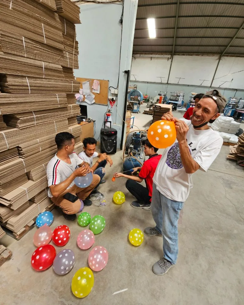 Karyawan JMP meniup balon warna-warni untuk persiapan lomba di lantai produksi.