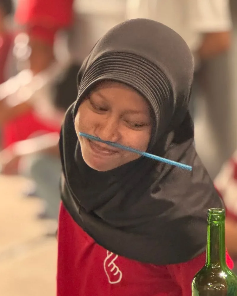 Karyawati JMP fokus bermain lomba memasukkan pensil ke botol dalam perayaan 17 Agustusan.