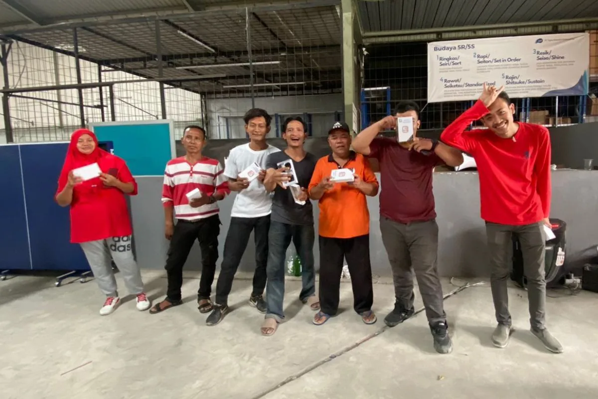 Pemenang lomba kemerdekaan JMP berbaris memegang hadiah, suasana meriah di lantai produksi.
