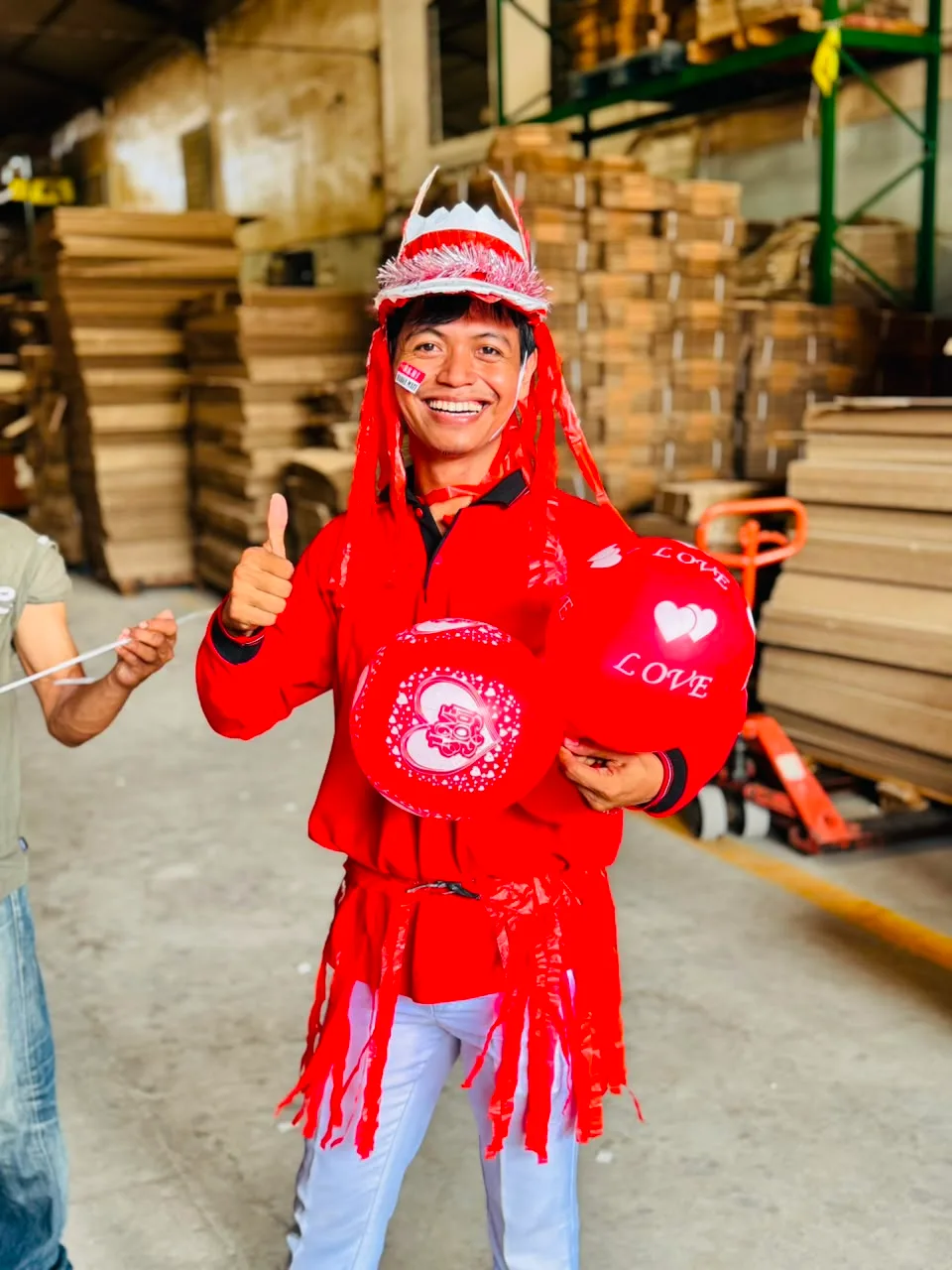 Juara 2 dress code mengacungkan jempol sambil memeluk dua balon merah bertuliskan LOVE, mengenakan jaket merah berumbai plastik dan hiasan kepala perak.