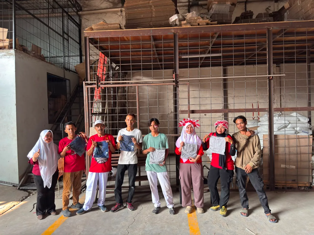 Juara 2 lomba angkat kaleng memegang handuk hadiah yang masih terbungkus plastik bening.