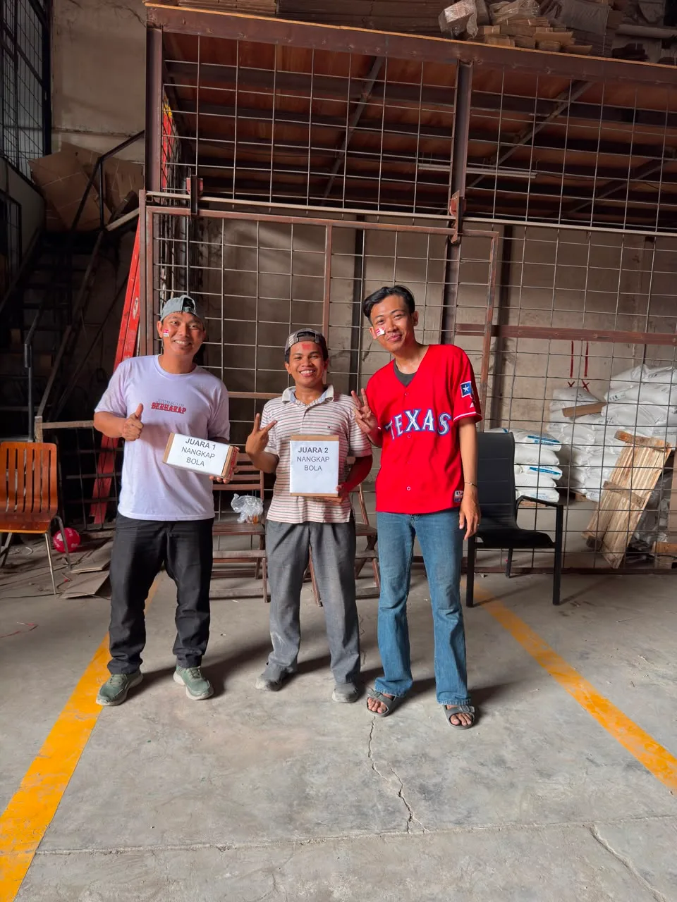 Juara 1 dan juara 2 lomba nangkap bola memegang kardus hadiah masing-masing, dengan kertas nama juara ditempel langsung di kardusnya.