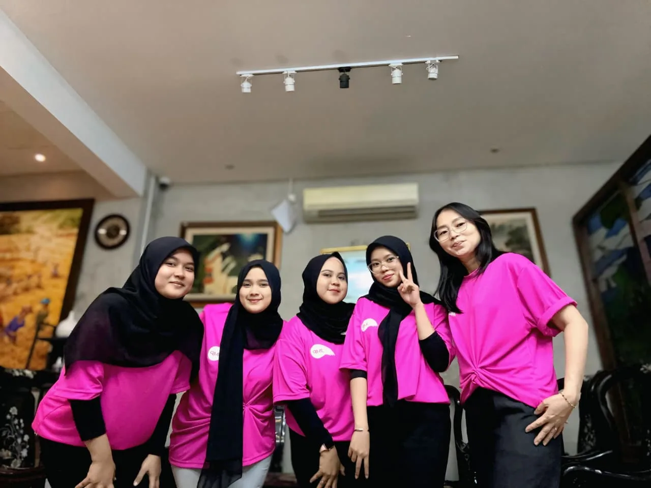 Lima staf kantor berkaus merah muda berfoto bersama di ruang kantor JMP.