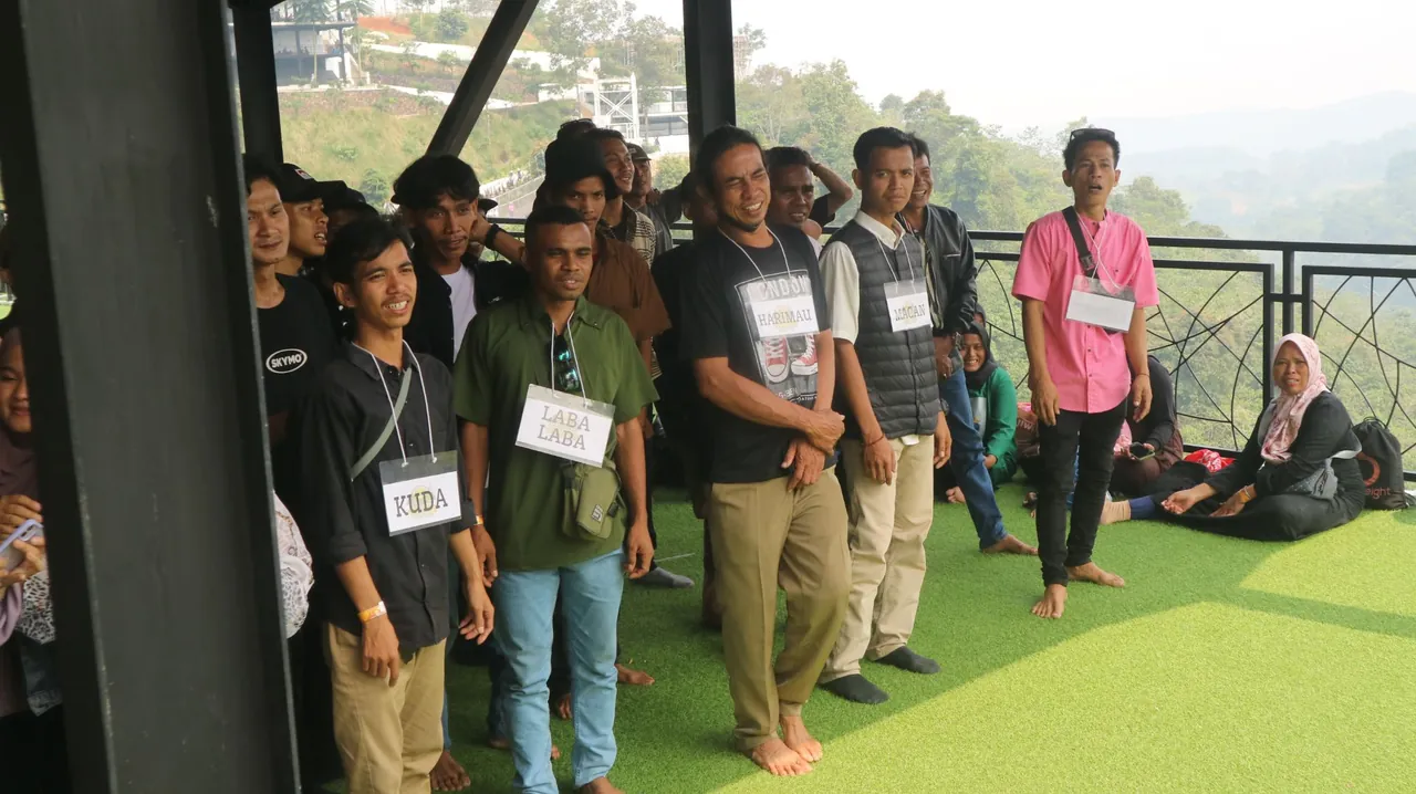 Sesi team building — karyawan JMP dengan tanda nama kelompok (Kuda, Harimau, Laba-Laba) sebelum lomba.