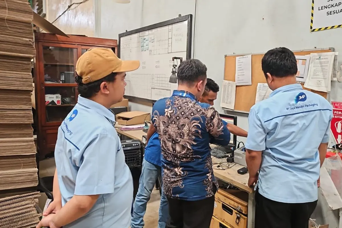 The auditor reviewing process records at a shop-floor workstation, beneath the workflow board and the Quality Policy sheet.