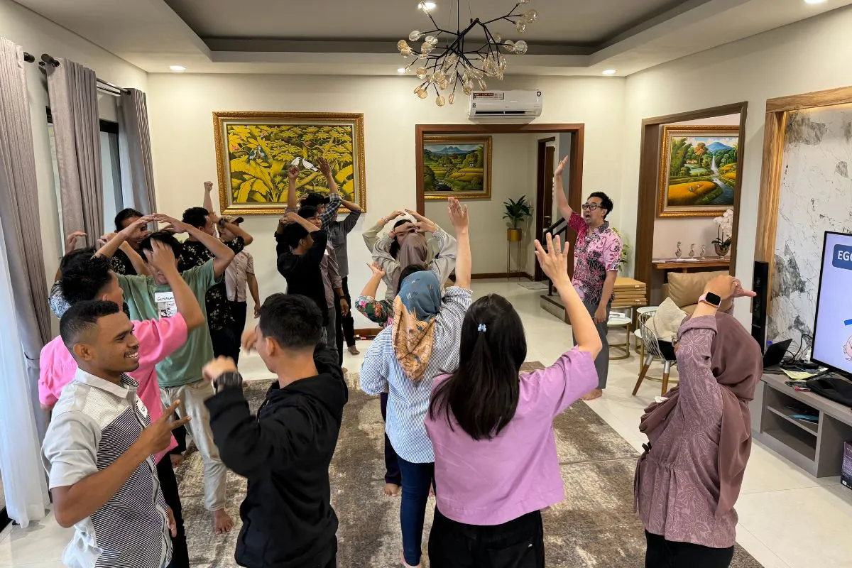Participants raising their hands through a warm-up routine led by the facilitator in the villa's main room.