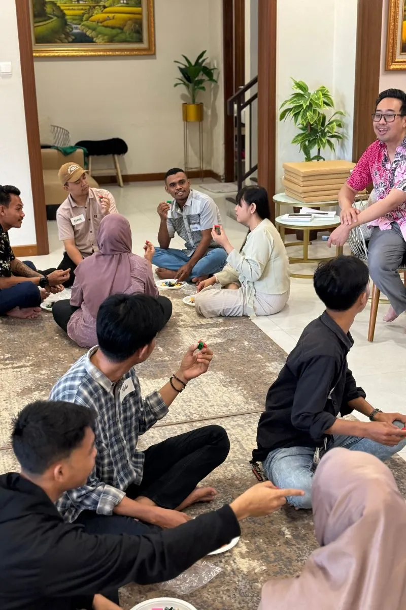 The team sitting in a circle on the floor, each person holding the small model they built.