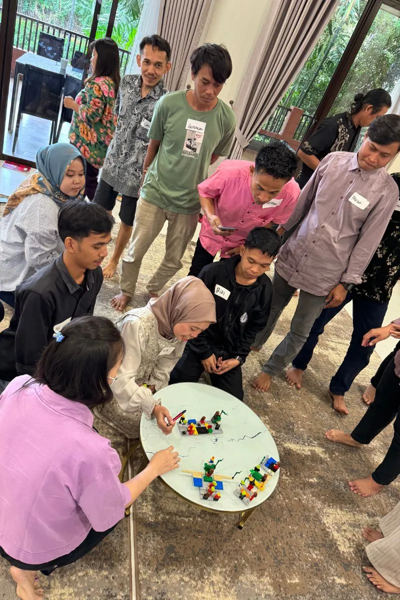 Participants gathered around the round table where the shared model was assembled, handwritten name tags on every shirt.