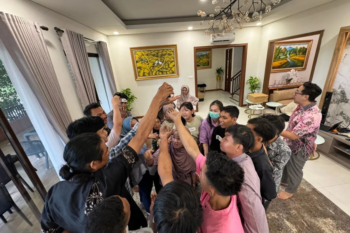 The whole group putting their hands together in the middle of the circle to close a session.