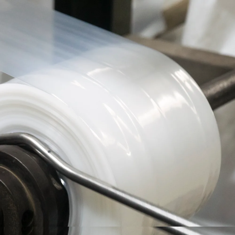 Film LDPE keluar dari mesin extrusion JMP — resin adalah komponen biaya terbesar di sebuah polybag.