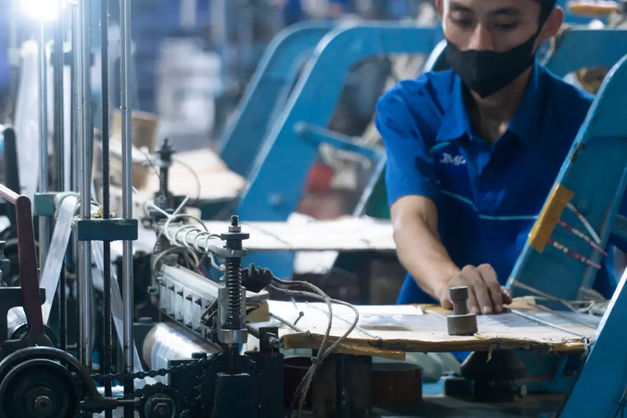 Operator JMP di mesin cutting dan sealing polybag — tempat gulungan film menjadi kantong satuan.